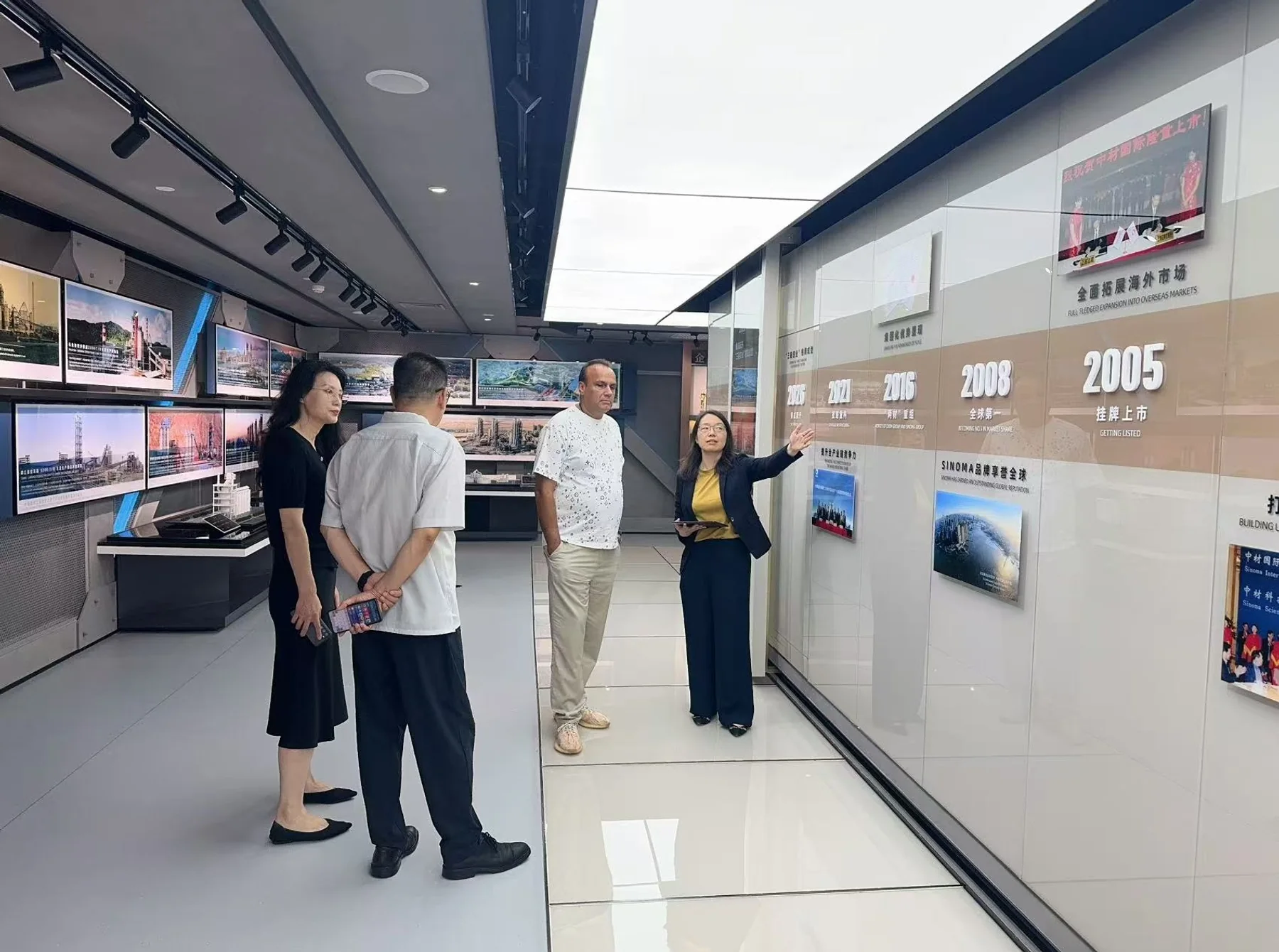 Visitors listening to an explanation beside a company history display in an exhibition hall.