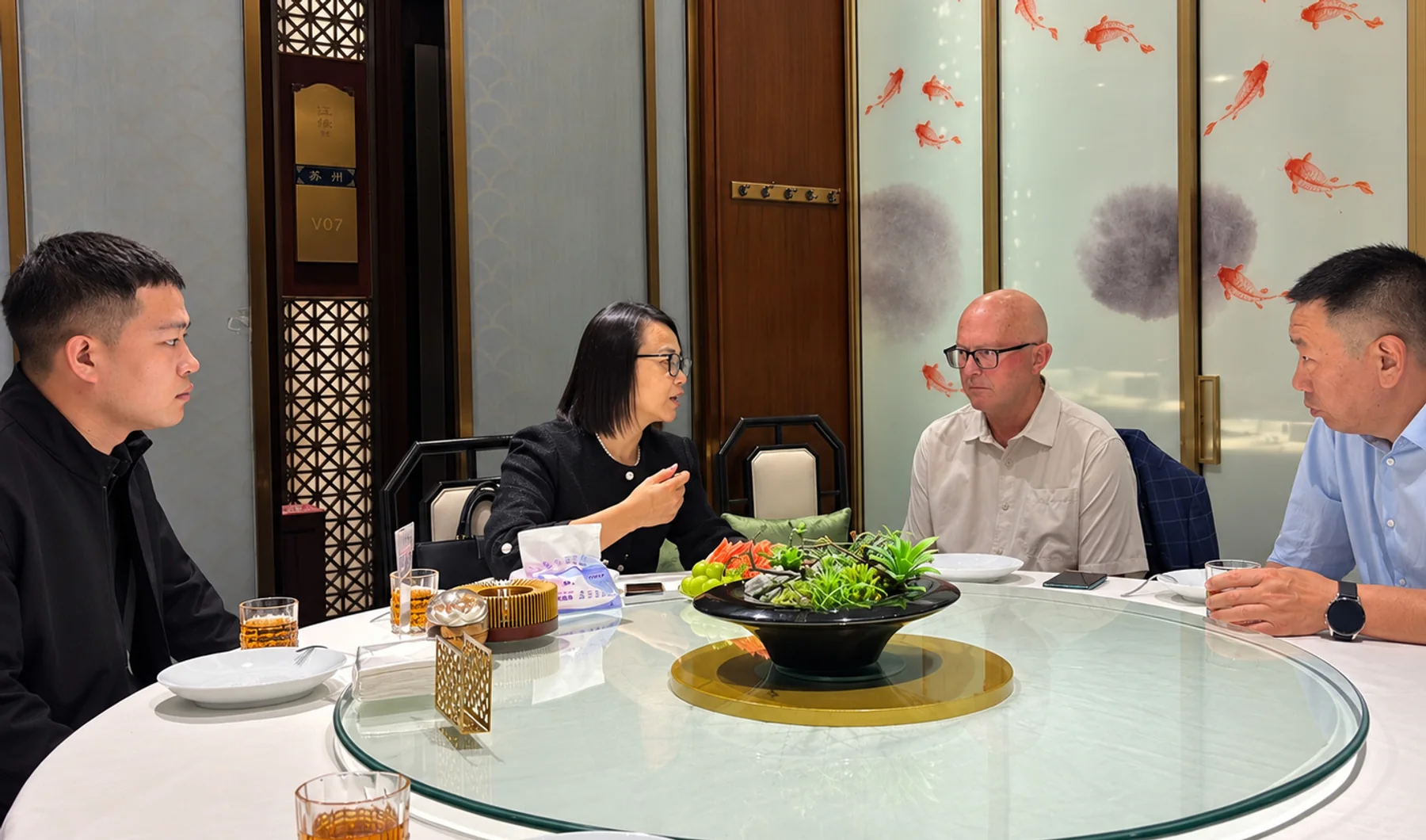 Four participants in conversation around a restaurant dining table.