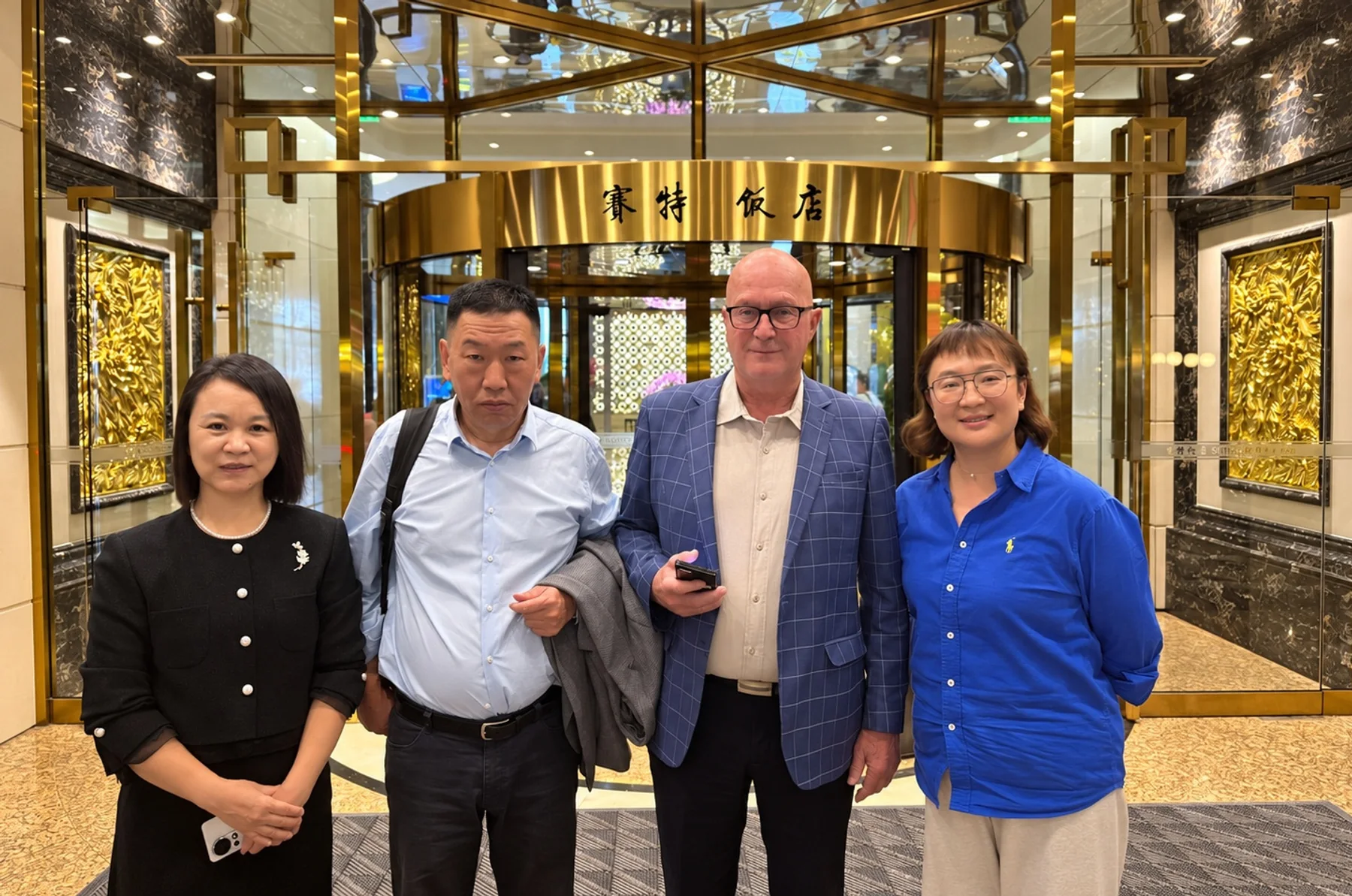 Four people photographed together at a hotel entrance during a business reception.